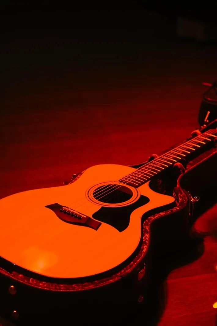 Guitare acoustique posée sur scène avec ambiance lumineuse rouge